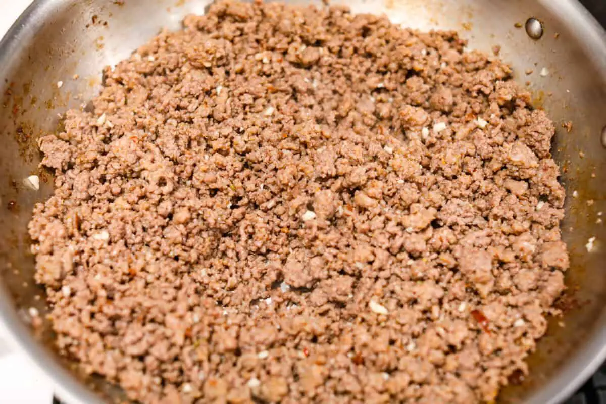 Overhead shot of garlic added to the cooked meat. 