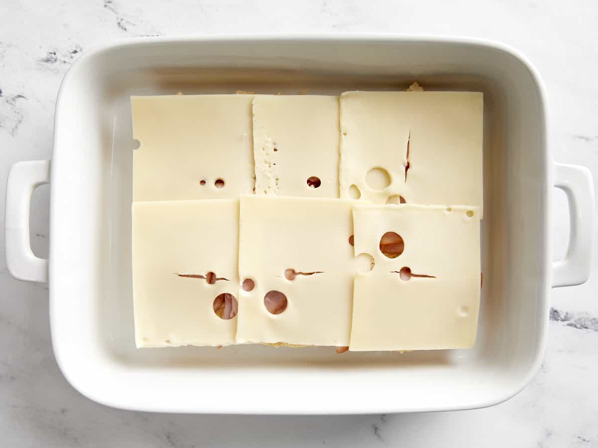Sechs Scheiben Schweizer Käse auf Schinkenscheiben.