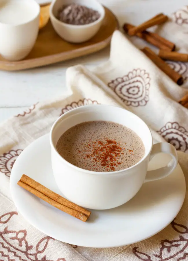 Kaffeetasse voller mexikanischer Schokolade mit einer Zimtstange an der Seite.
