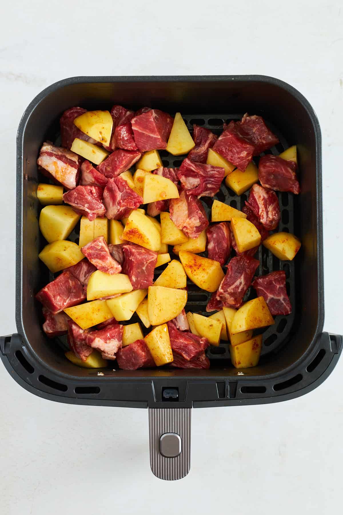 Rohes Steak und Kartoffeln in einer Heißluftfritteuse. 