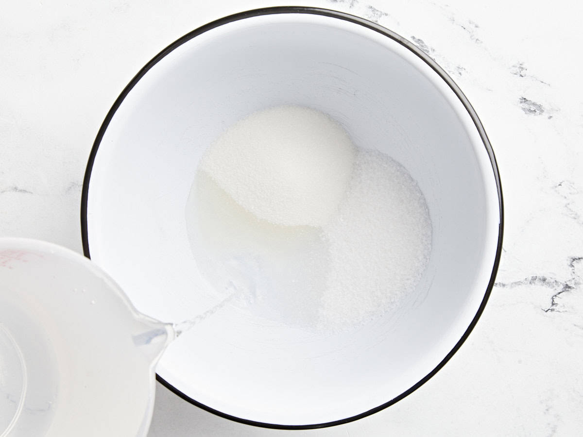 Wasser über Zucker und Salz in einer großen weißen Schüssel gießen.