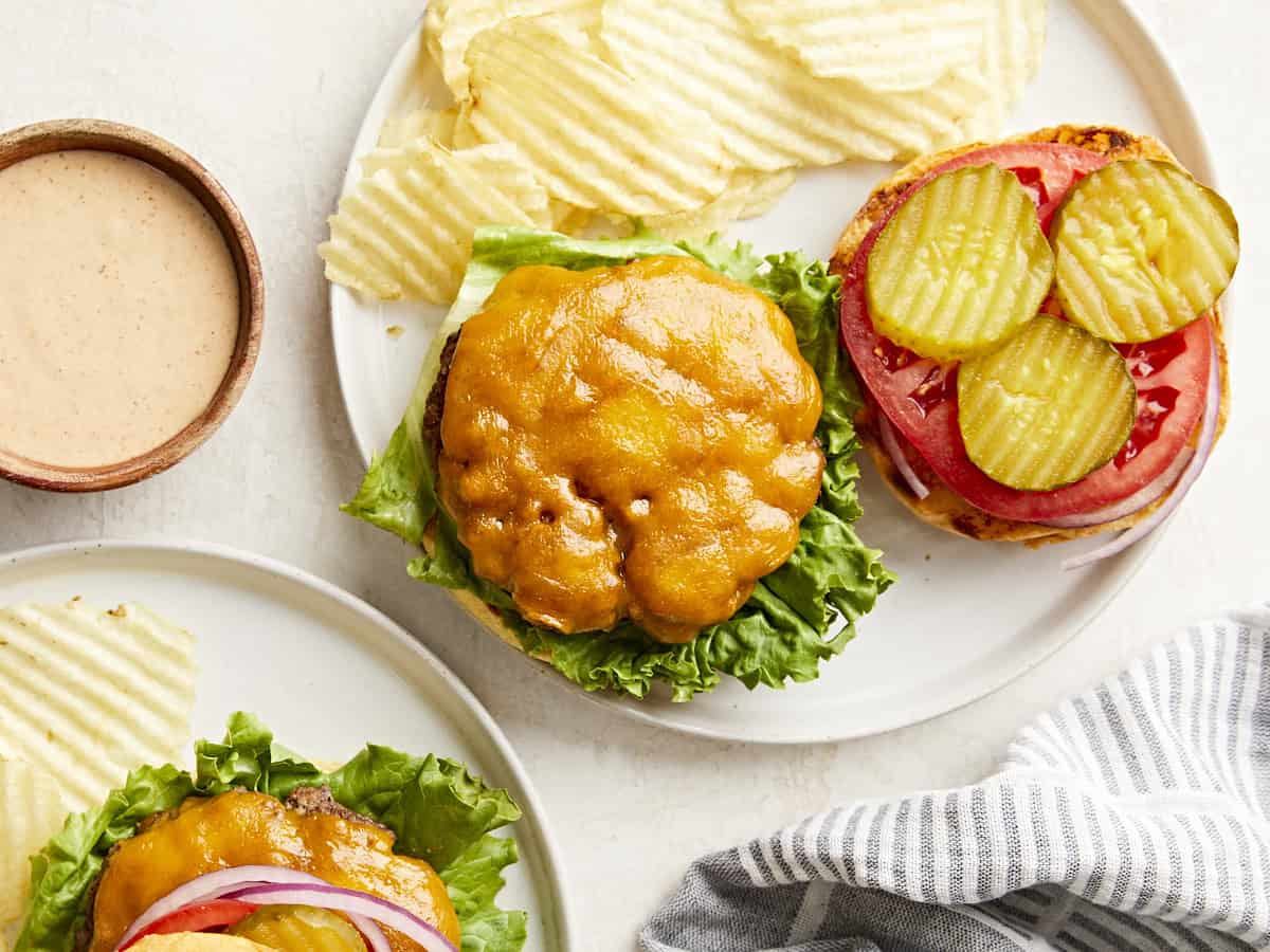 Draufsicht auf hausgemachte Hamburger auf einem Teller mit Belag und Pommes an der Seite.