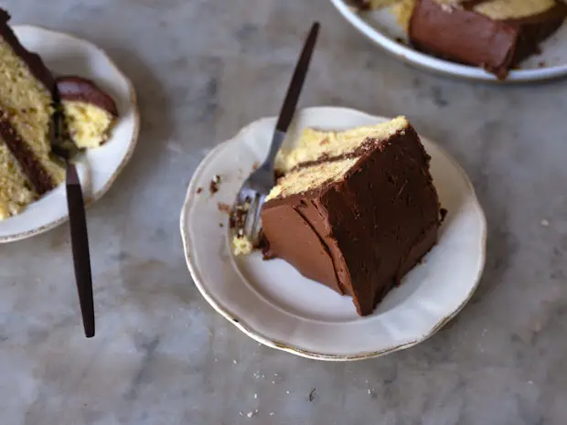 Stücke von gelbem Kuchen mit Schokoladenglasur auf einer Marmorarbeitsplatte angeordnet