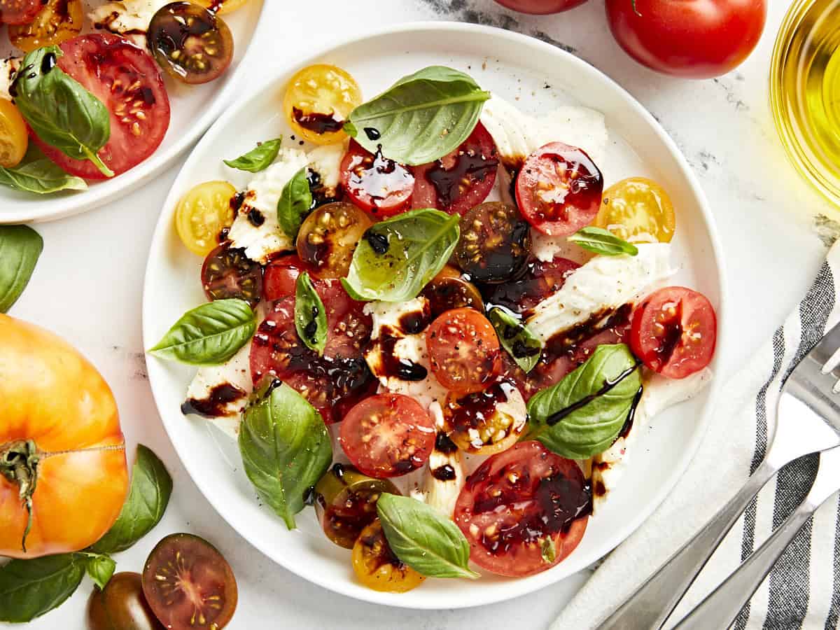 overhead view of a serving of caprese salad on a white plate with balsamic glaze.