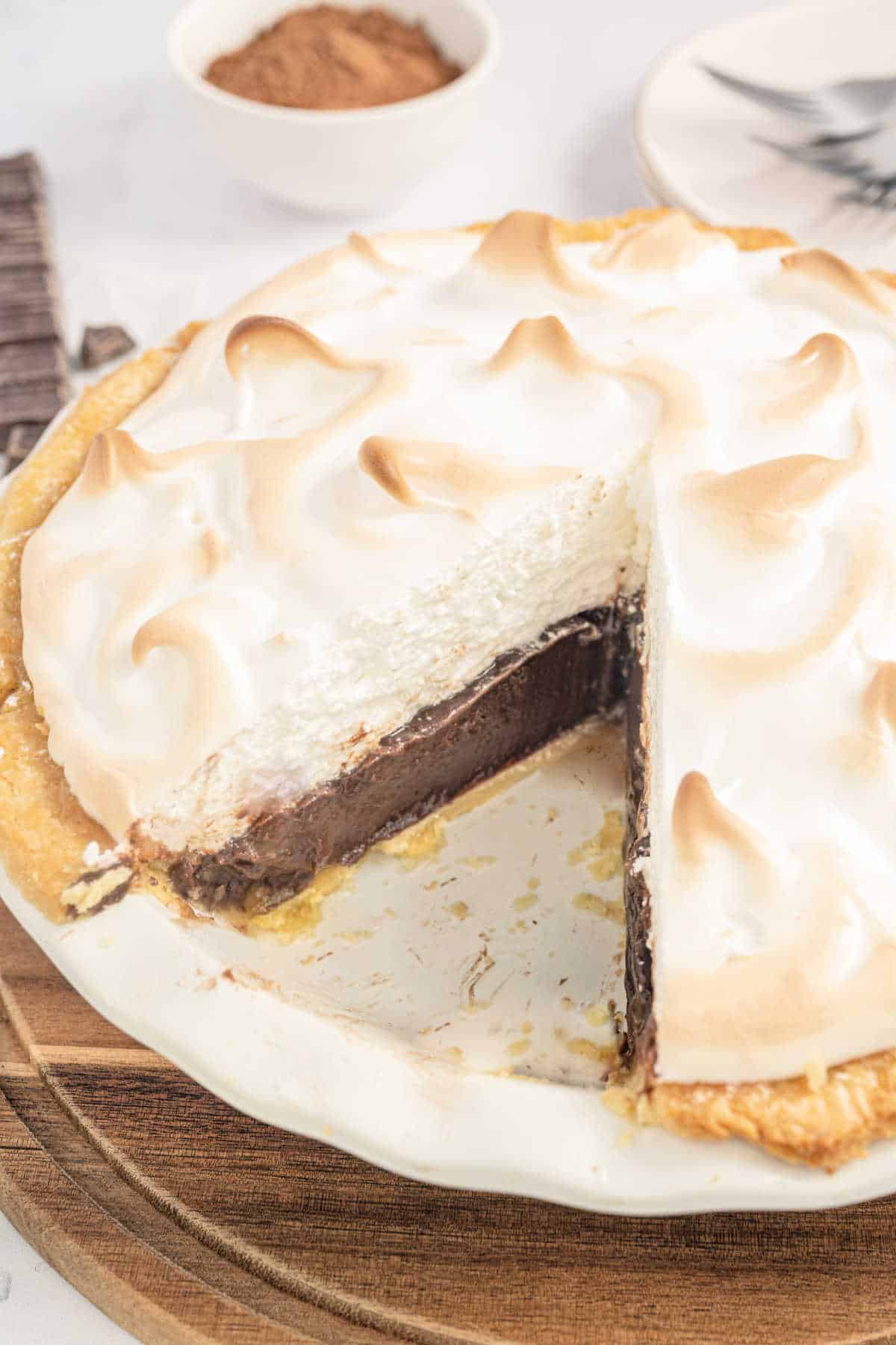 Schokoladenkuchen mit Baiserhaube, von dem ein Stück abgenommen wurde.