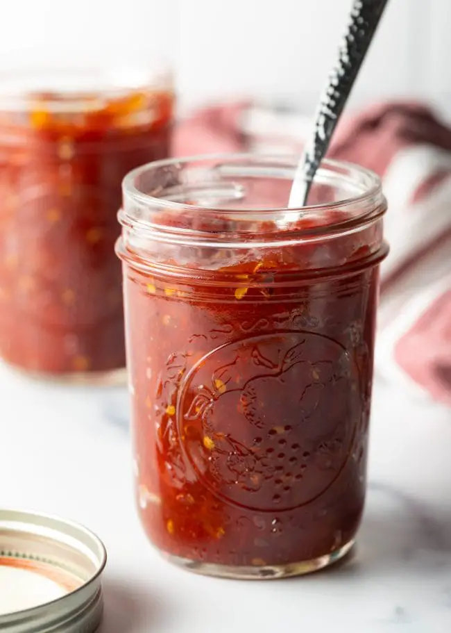 Volles Glas hausgemachte Tomatenmarmelade mit Löffel darin.