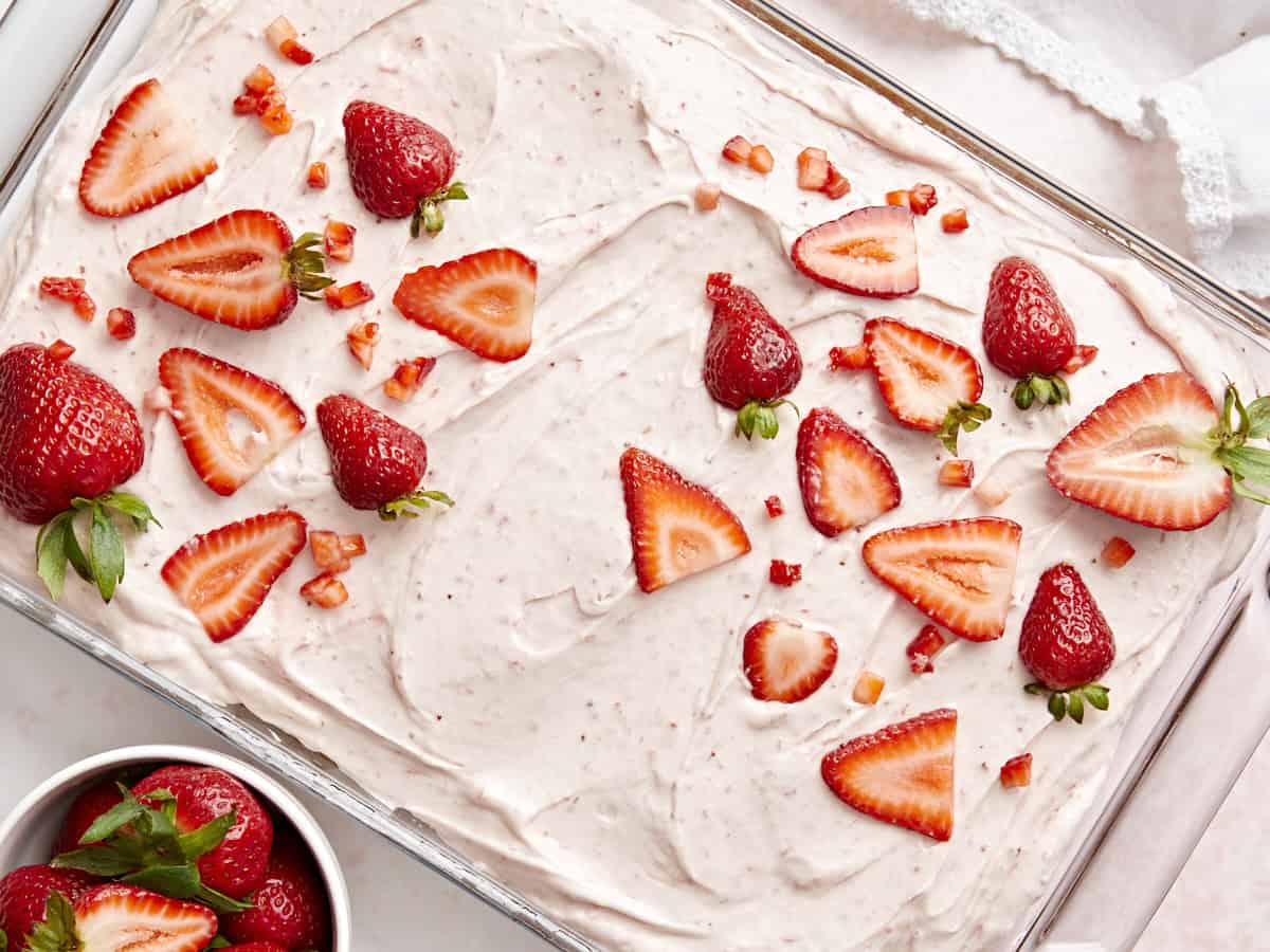 Draufsicht auf einen Erdbeerblechkuchen mit Erdbeerglasur und frischen Erdbeeren obendrauf.