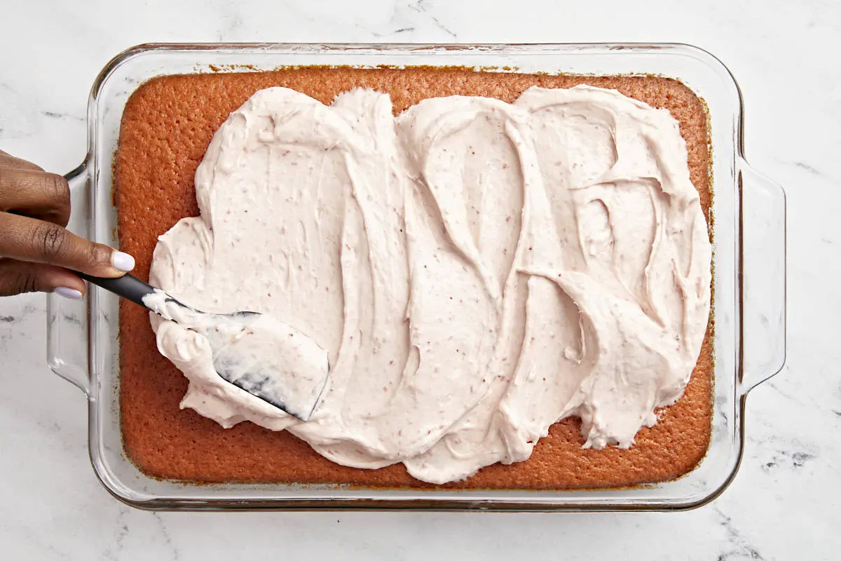 Erdbeer-Zuckerguss wird auf Erdbeerkuchen gestrichen.