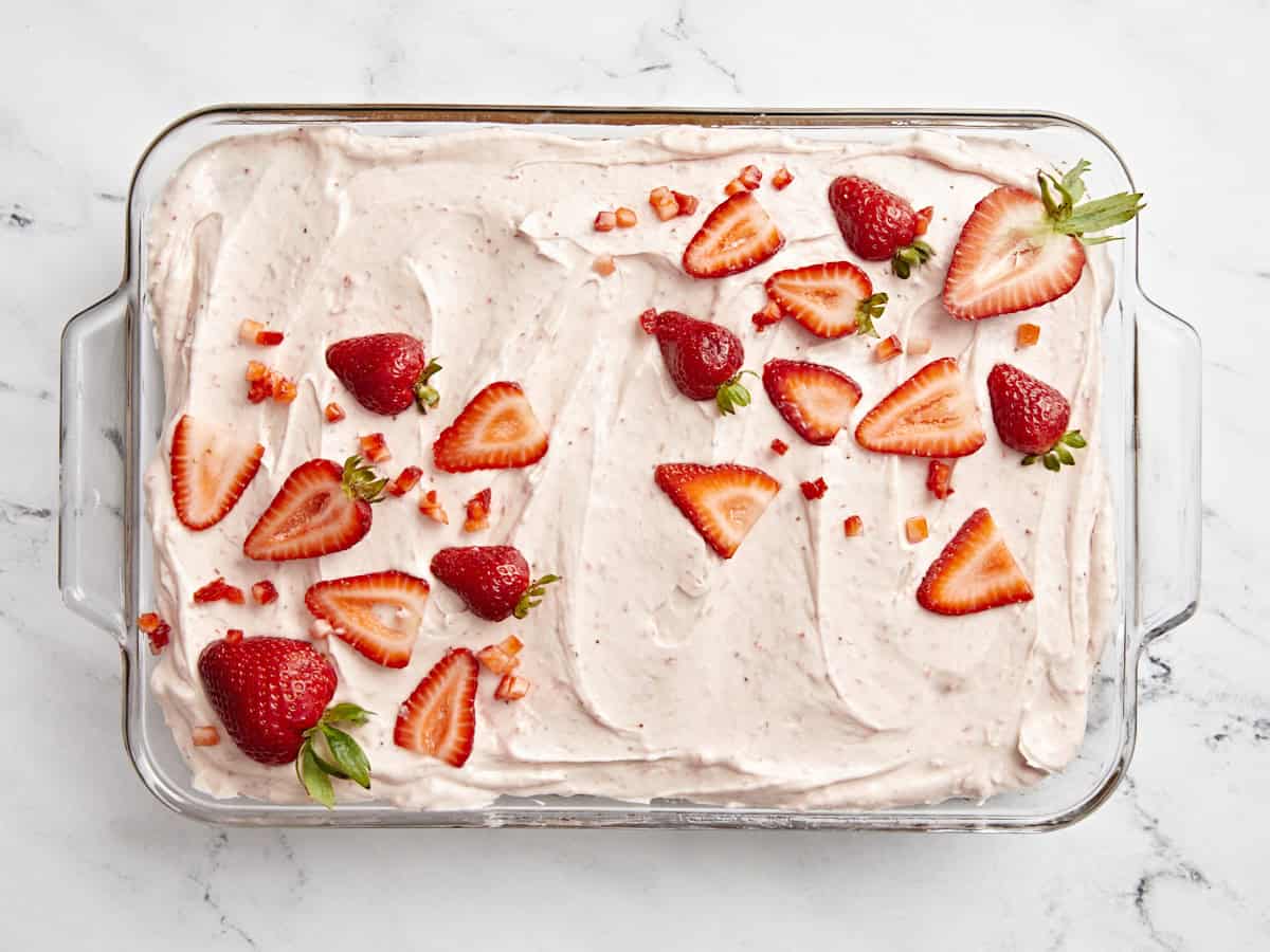 Draufsicht auf einen Erdbeerblechkuchen mit Erdbeerglasur und frischen Erdbeeren obendrauf.