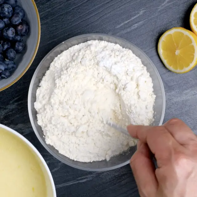 Trockene Zutaten werden gemischt, um einen Zitronen-Blaubeer-Gugelhupf zu backen.