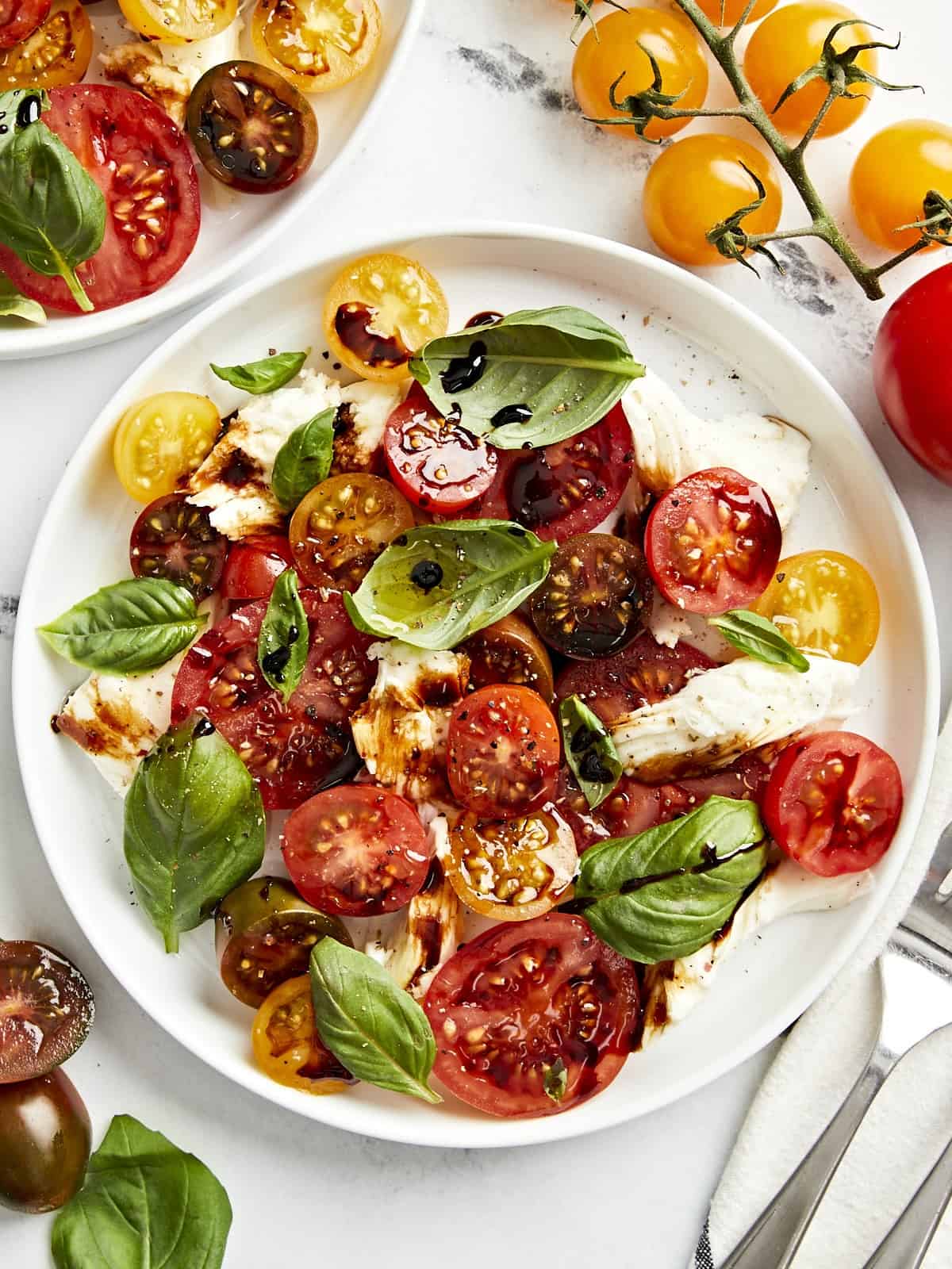 Draufsicht auf eine Portion Caprese-Salat auf einem weißen Teller mit Balsamico-Glasur.