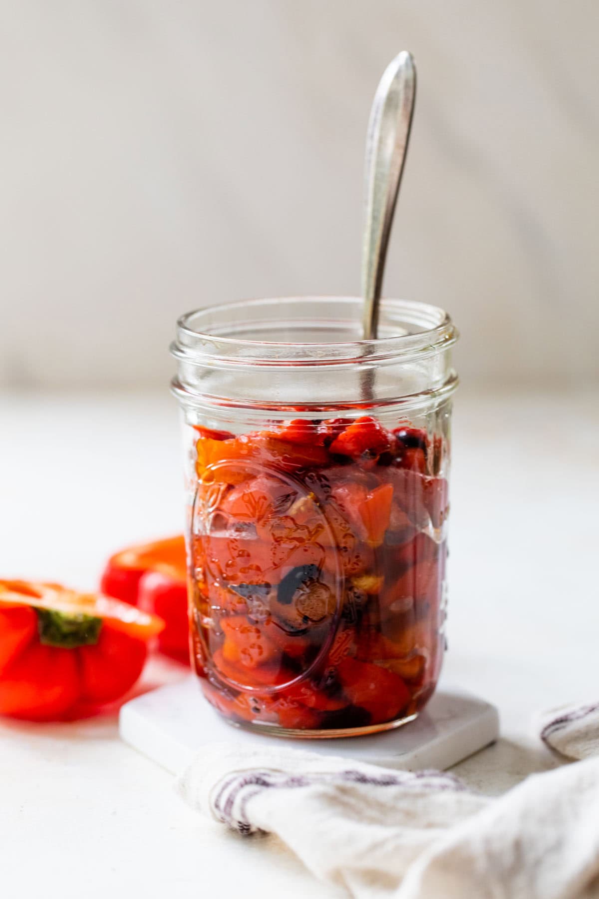 Glas mit gerösteten roten Paprika mit Löffel