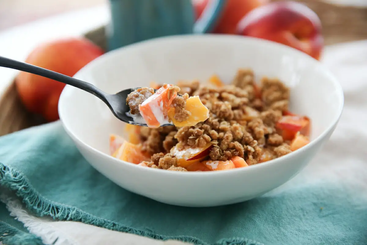 fruit, cream, and crumble topping over peaches