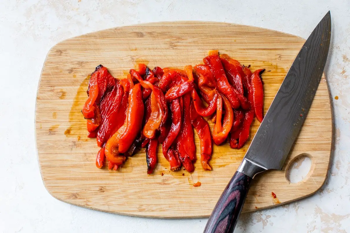 Geröstete rote Paprika in Scheiben geschnitten auf Schneidebrett