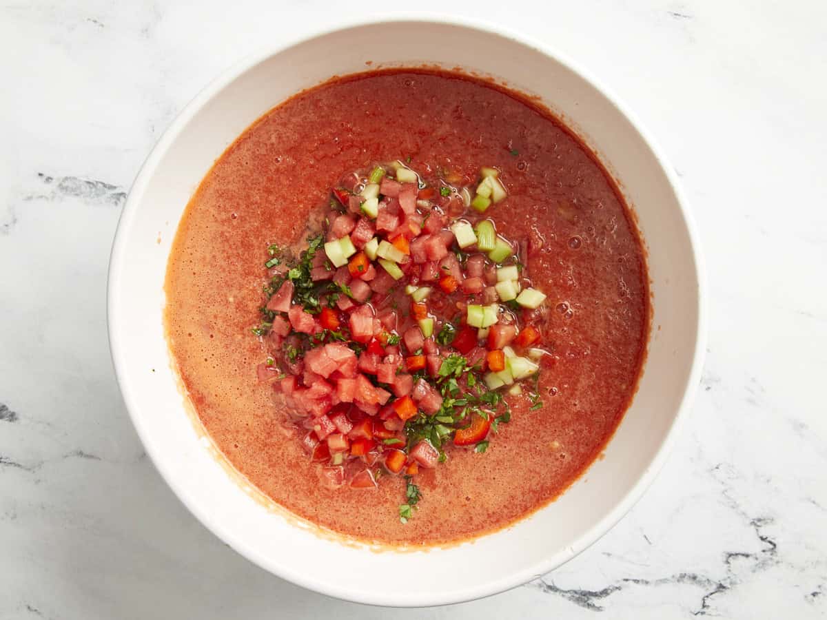 eine Schüssel Wassermelonen-Gazpacho, garniert mit gewürfeltem Obst und Gemüse.