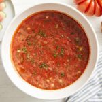 overhead view of watermelon gazpacho in a white bowl with minced fresh herbs.