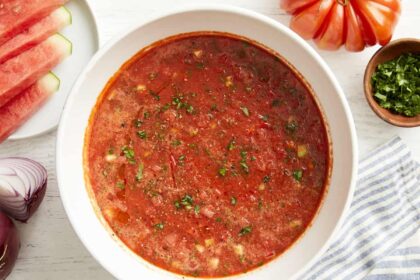 overhead view of watermelon gazpacho in a white bowl with minced fresh herbs.