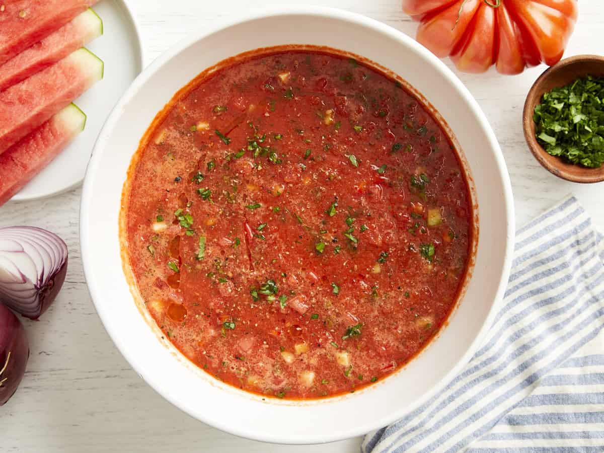 overhead view of watermelon gazpacho in a white bowl with minced fresh herbs.