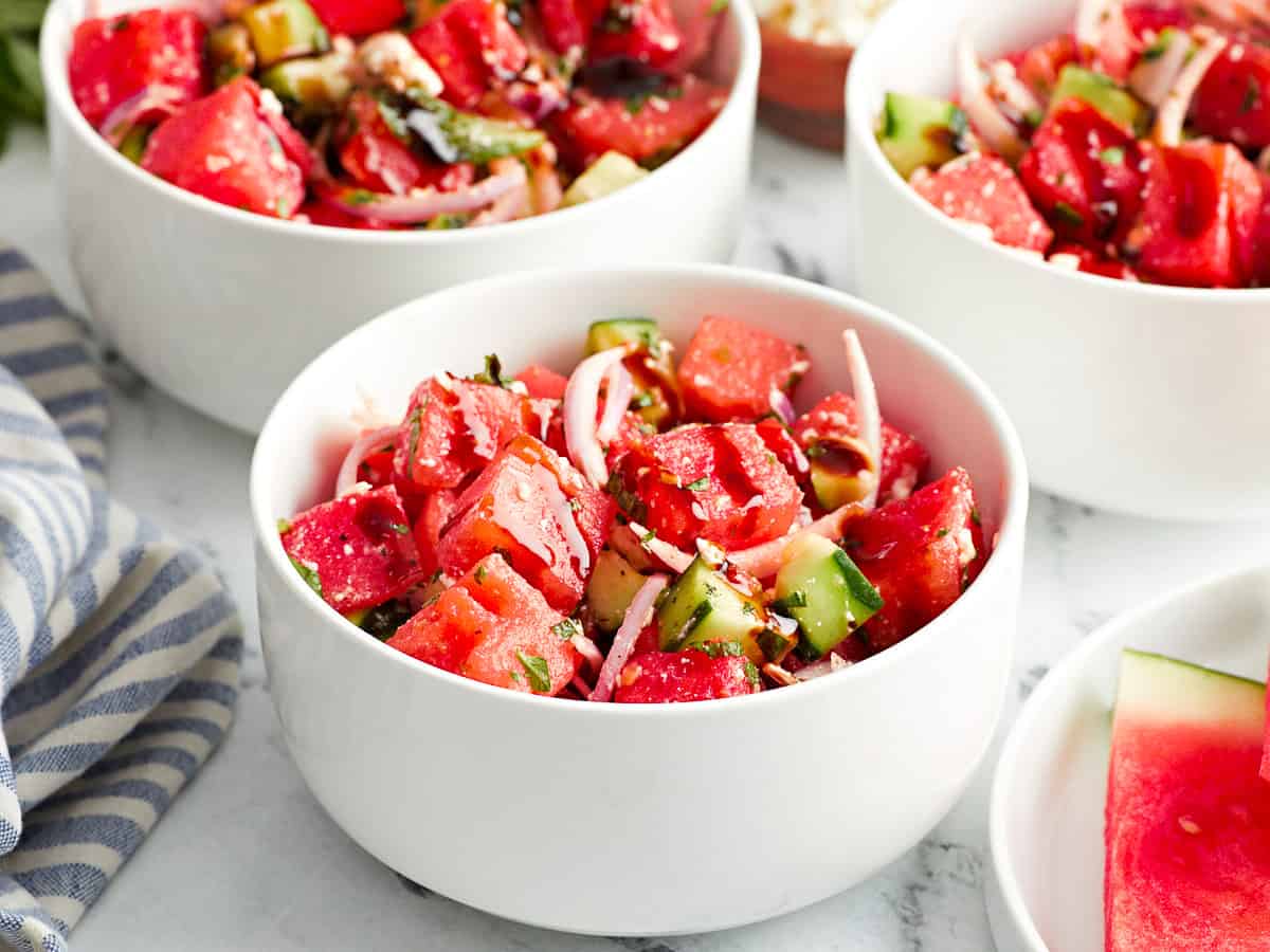 Seitenansicht von Portionen Wassermelonen-Feta-Salat in weißen Schüsseln mit Balsamico-Glasur.