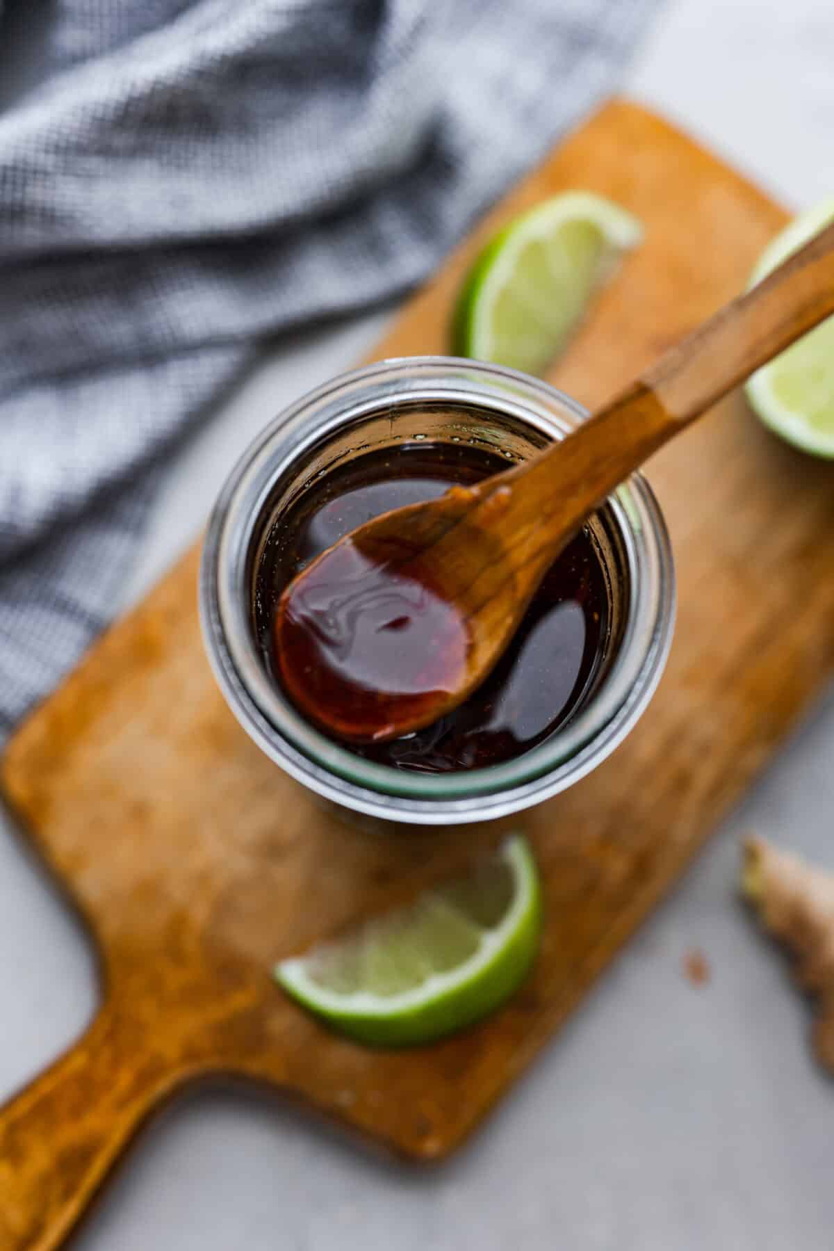 Draufsicht auf einen Holzlöffel, der in ein Glas mit Poke-Sauce eintaucht. 