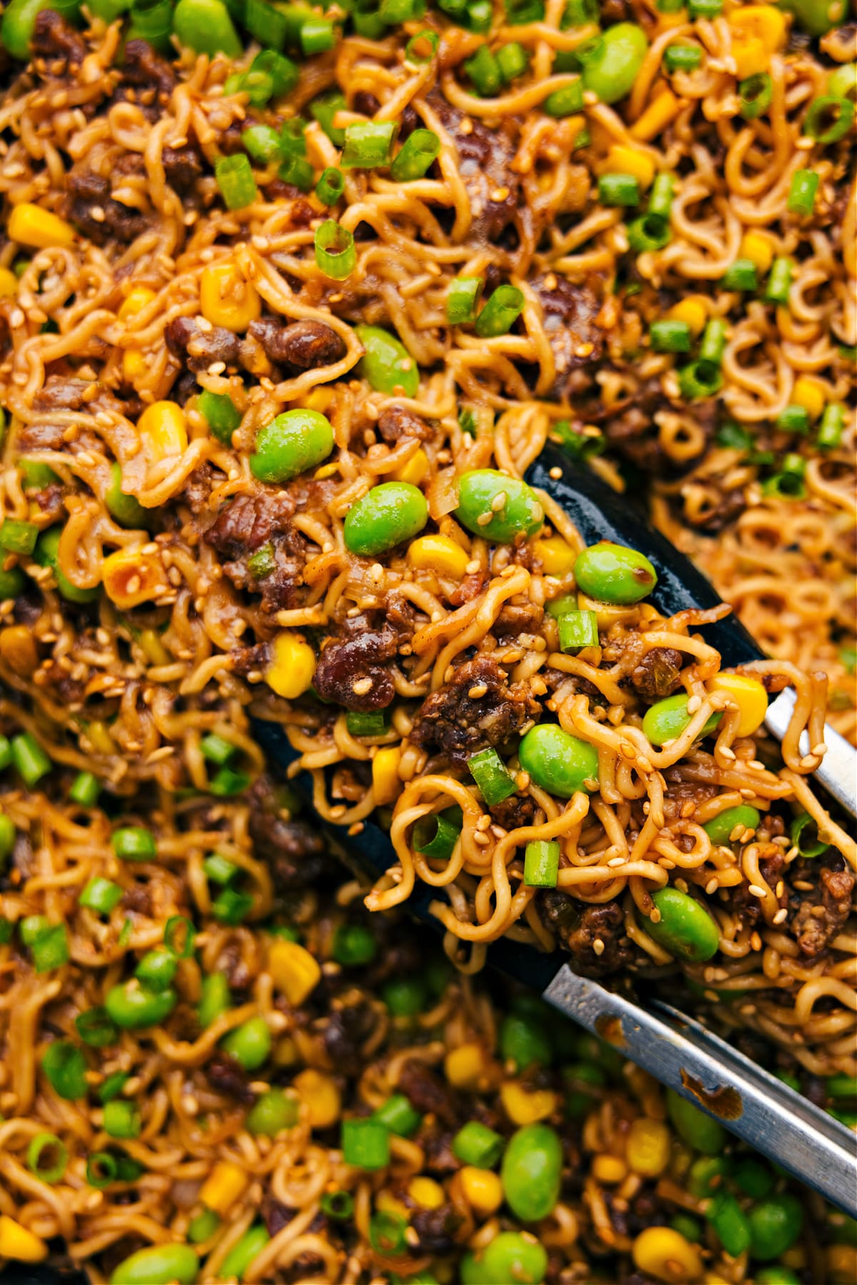 Pork Ramen Stir Fry being picked up with tongs ready to be served and enjoyed.