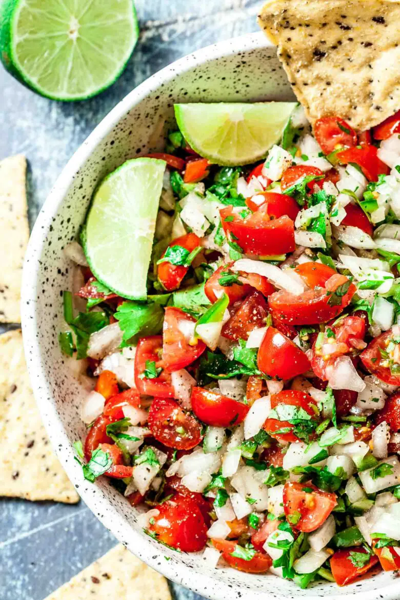 Eine Schüssel frisches Pico de Gallo mit gewürfelten Tomaten, Zwiebeln, Koriander und Limettenspalten, dazu Tortillachips.