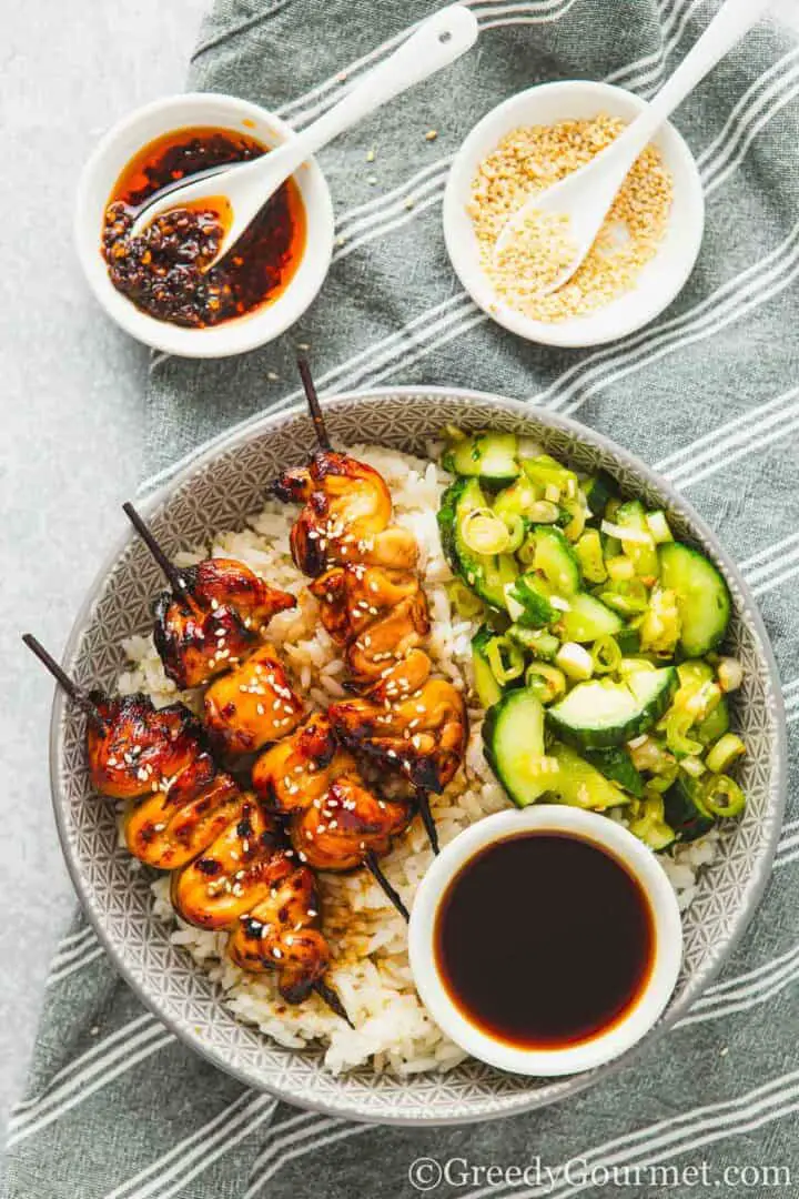 Yakitori-Hähnchenspieße serviert mit Reis und Gurkensalat.