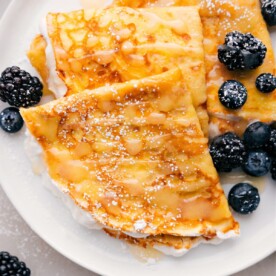 Teller mit drei Crêpes, darüber geträufelt mit Beeren und Sirup.