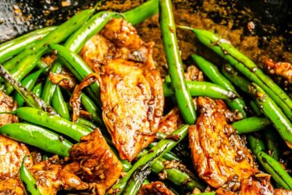 stir fry sauce coats green beans and thinly sliced chicken in the wok