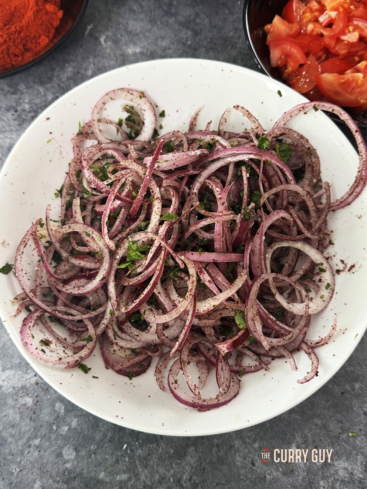 Die Salatzutaten vermischen. Geschnittene Zwiebeln, Sumach, Salz, Petersilie und Olivenöl.