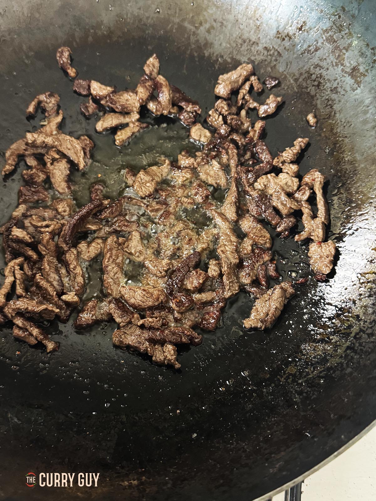 Das geschmorte Rindfleisch in Öl im Wok anbraten.