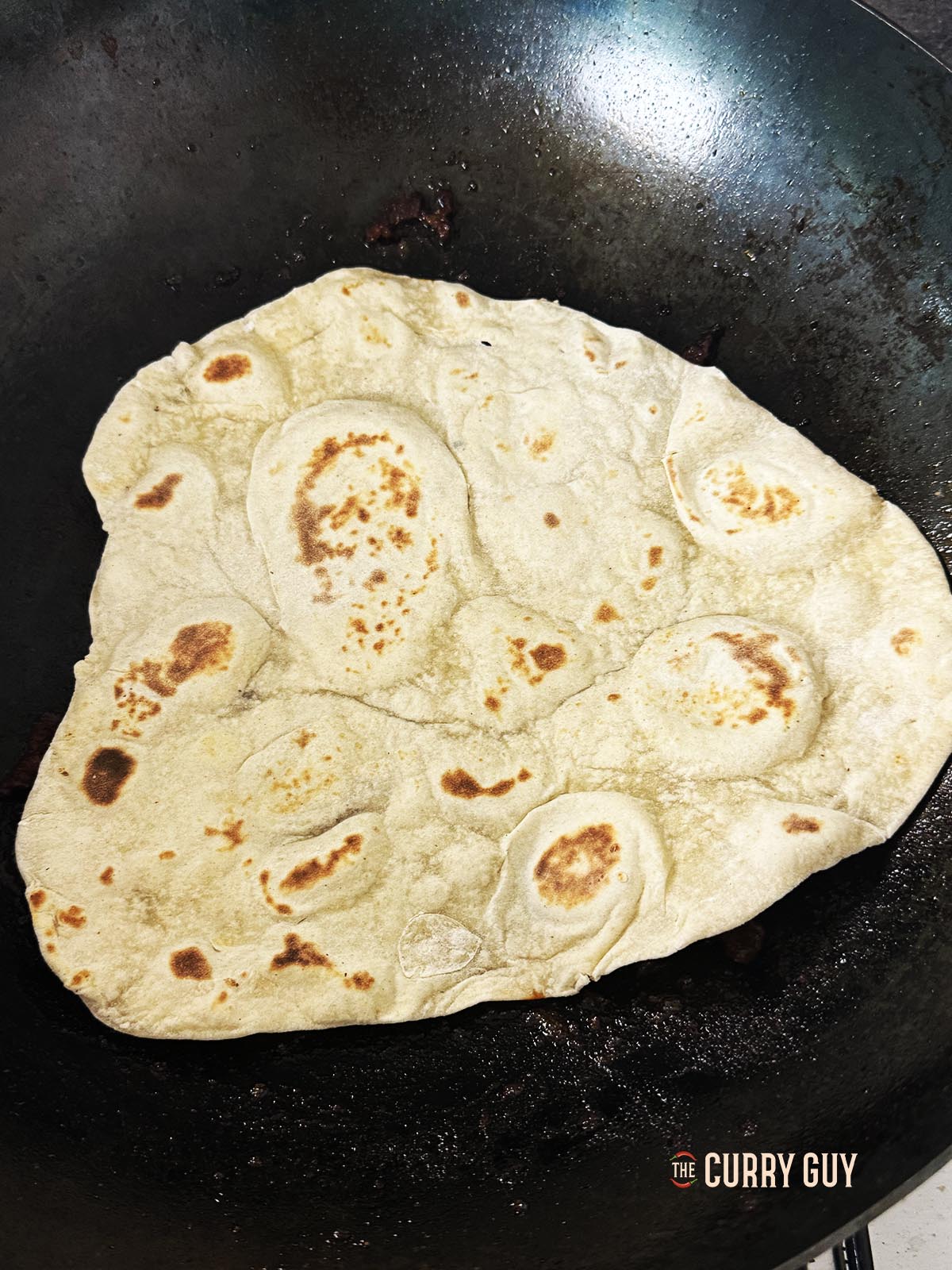 Drücken Sie ein Lavesh-Brot in das Fleisch und die Soße, damit es etwas von der Soße und dem Öl aufsaugt.