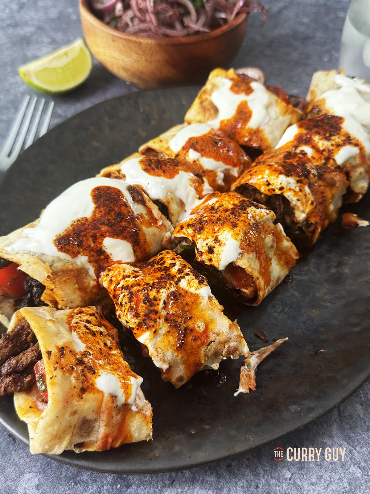 Tantuni mit Joghurtsauce und gewürzter Buttersauce in mundgerechte Stücke geteilt.