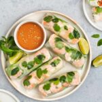 Vietnamese summer rolls on a platter with peanut dipping sauce and limes