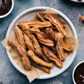 Teller Churros, serviert mit einer Beilagenschale reichhaltiger Schokoladensoße.