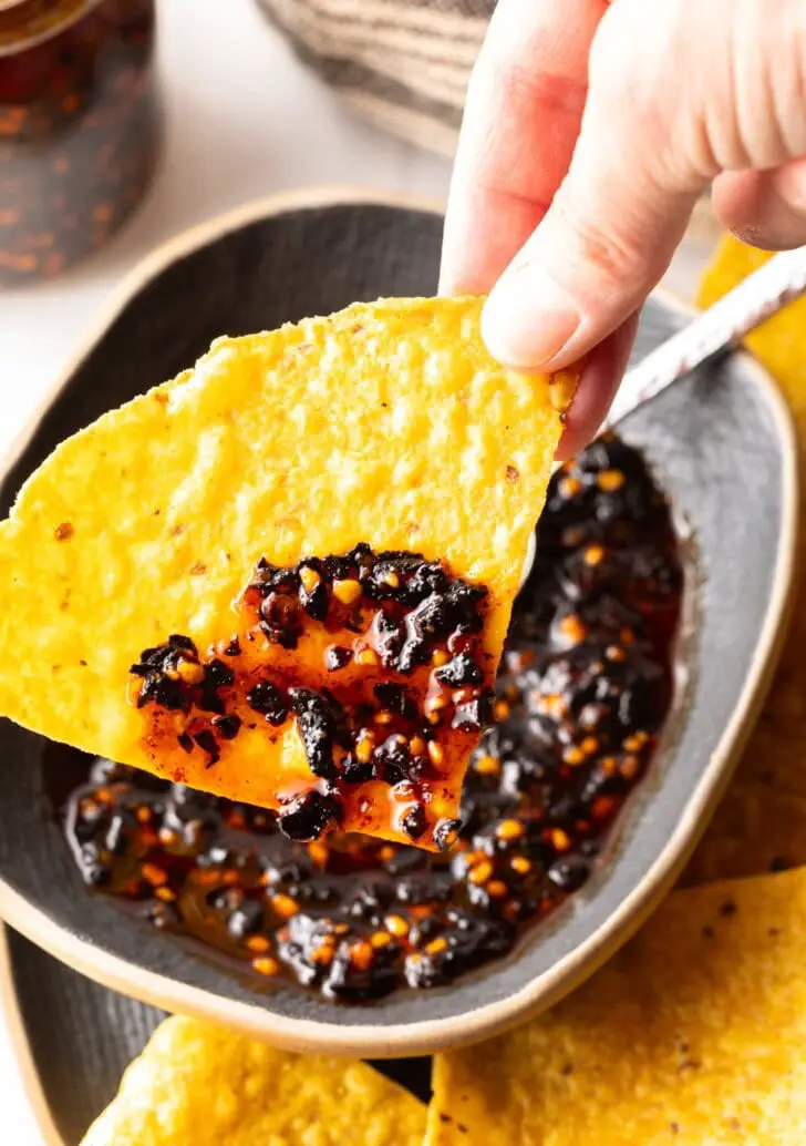 Tortillachip mit einer Kugel roter Salsa Macha. Die Salsa de Chile de Arbol wird der Kamera gezeigt.