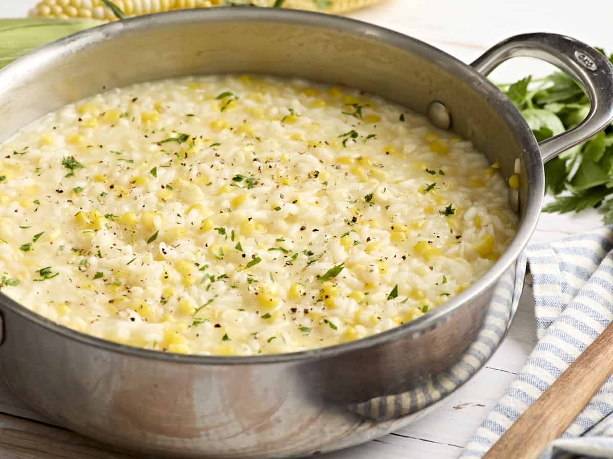 Zuckermaisrisotto in einer Pfanne, garniert mit frischen Kräutern.