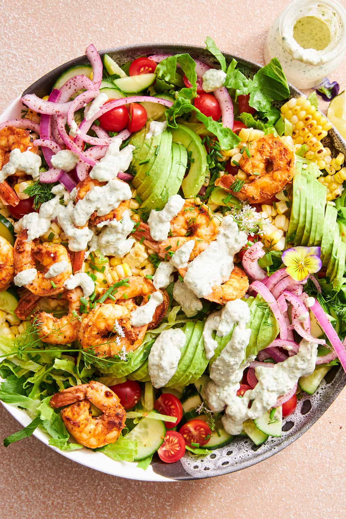 Eine Schüssel Garnelen-Avocado-Salat, garniert mit cremigem Tahini-Dressing. 