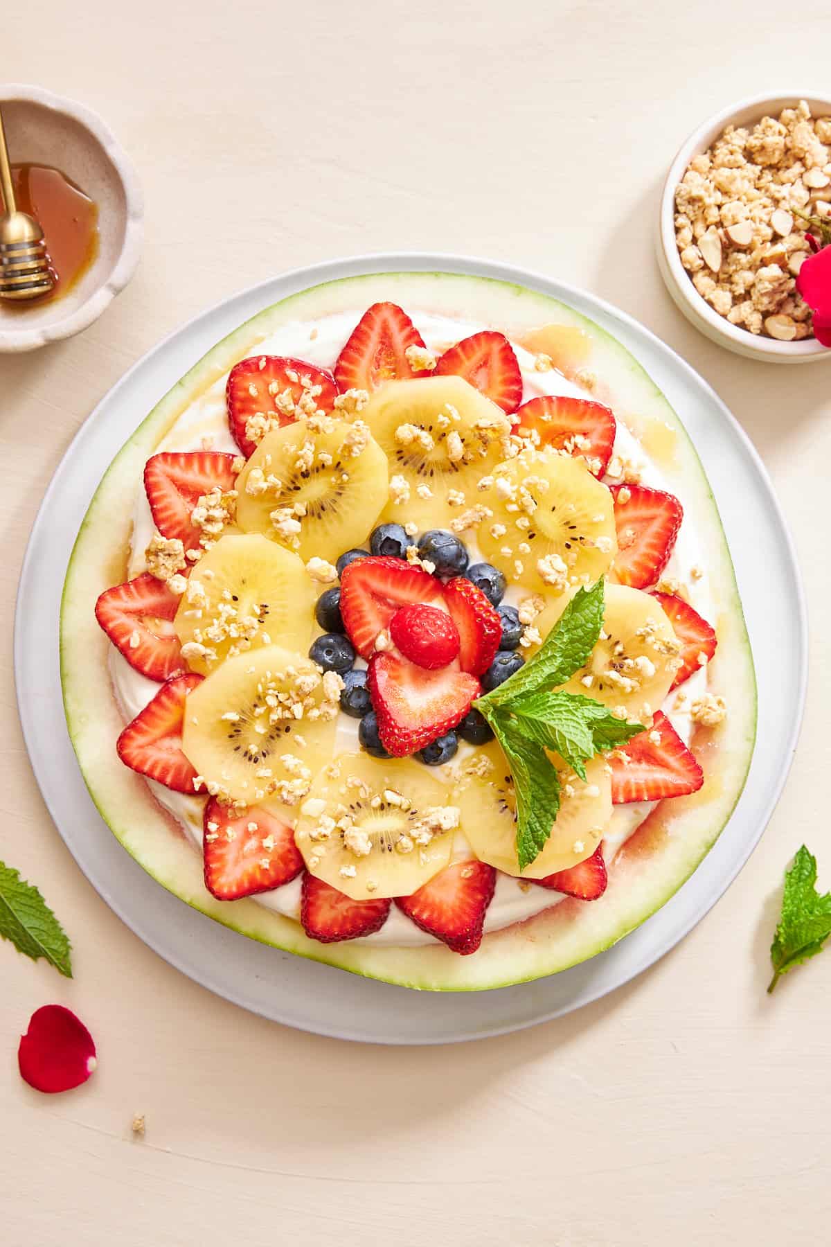 Wassermelonenpizza mit Joghurt, Obst, Müsli und Minze belegt. 