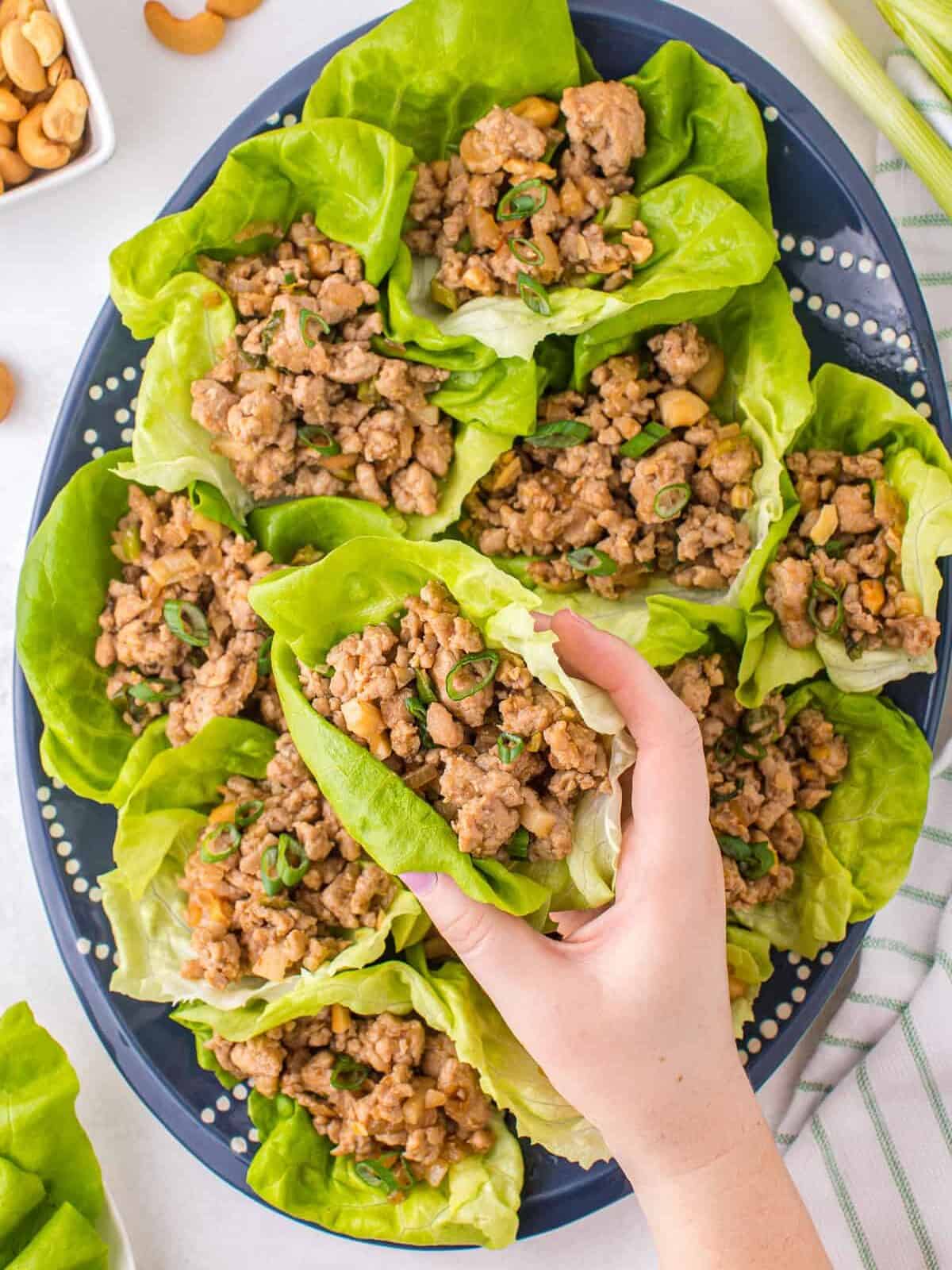 lifting up chicken lettuce wrap from platter