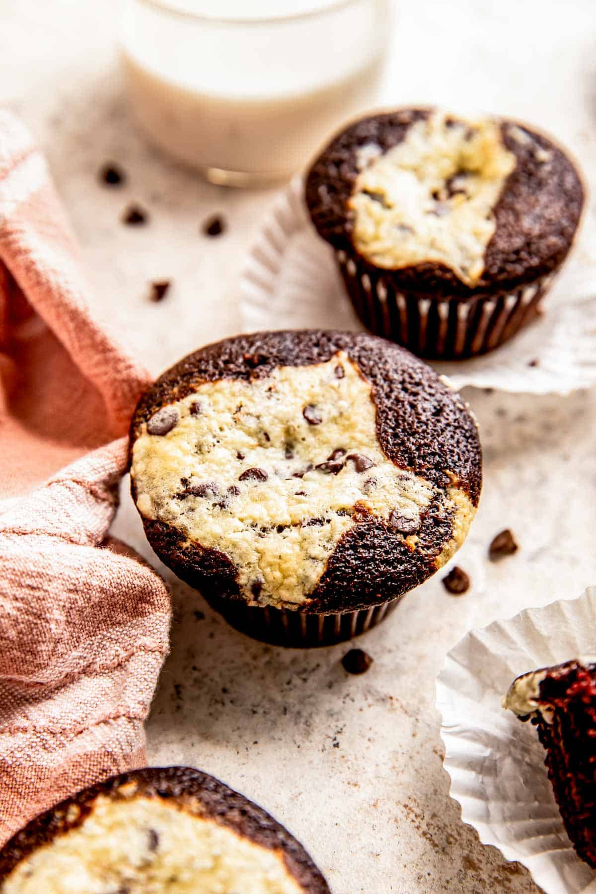 Ein Schokoladen-Frischkäse-Muffin liegt auf einer grauen Oberfläche neben einem anderen Cupcake