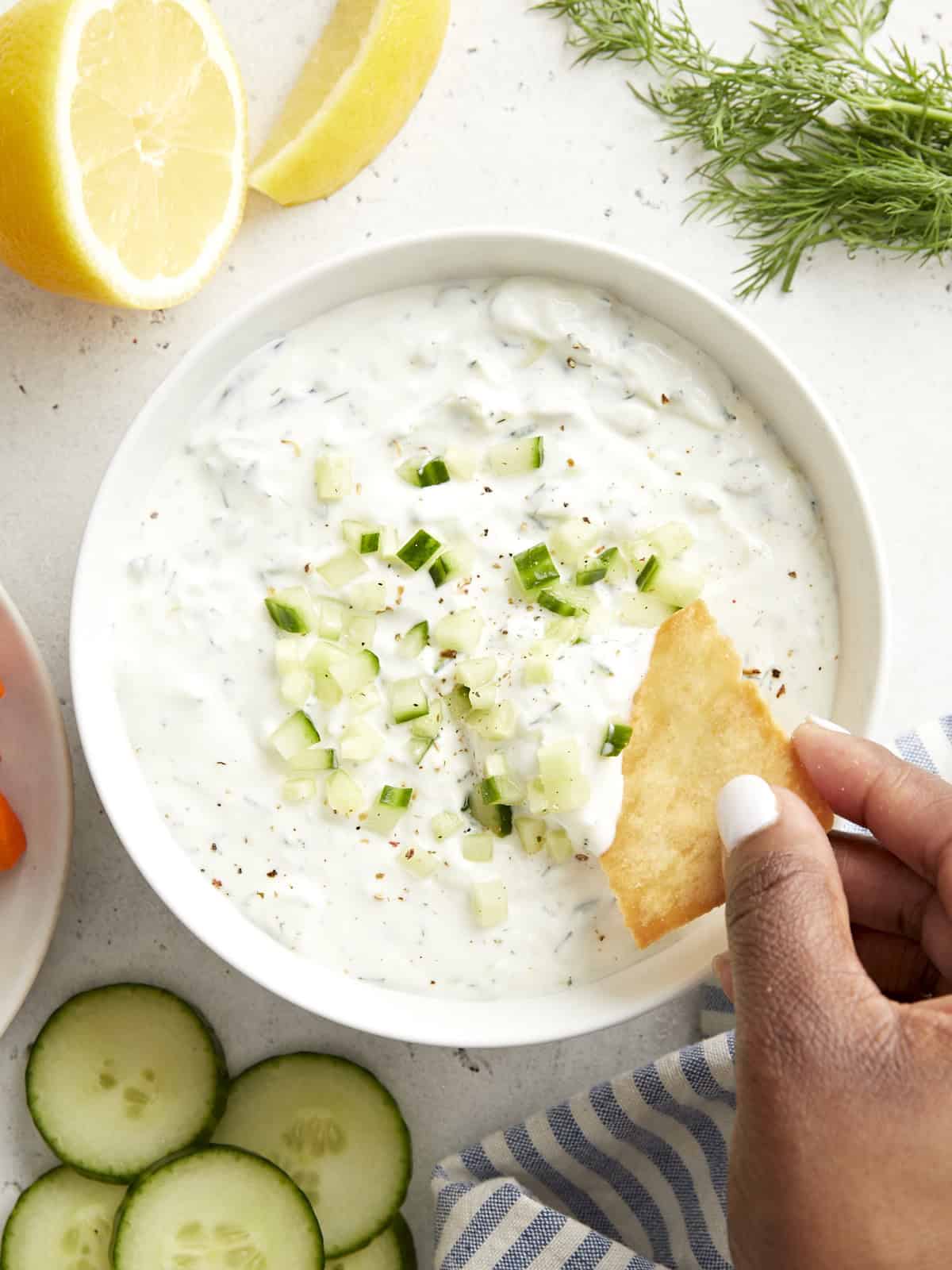 Draufsicht auf Tzatziki-Sauce mit einem Pita-Chip, der in die Sauce getaucht wird.