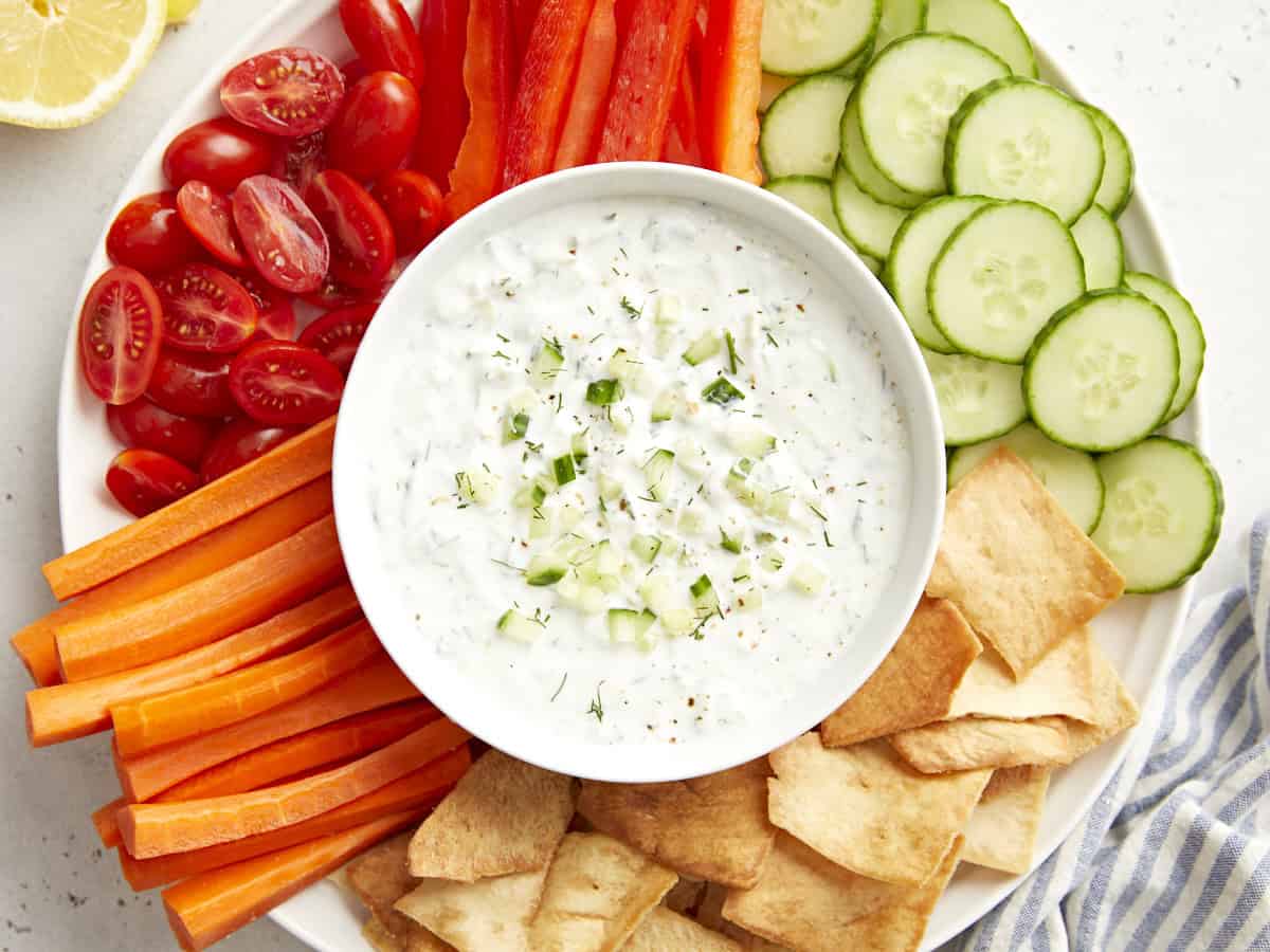 Draufsicht auf Tzatziki-Sauce in einer Servierschüssel auf einer Gemüseplatte.