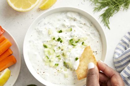 Overhead view of tzatziki sauce with a pita chip being dipped in the sauce.