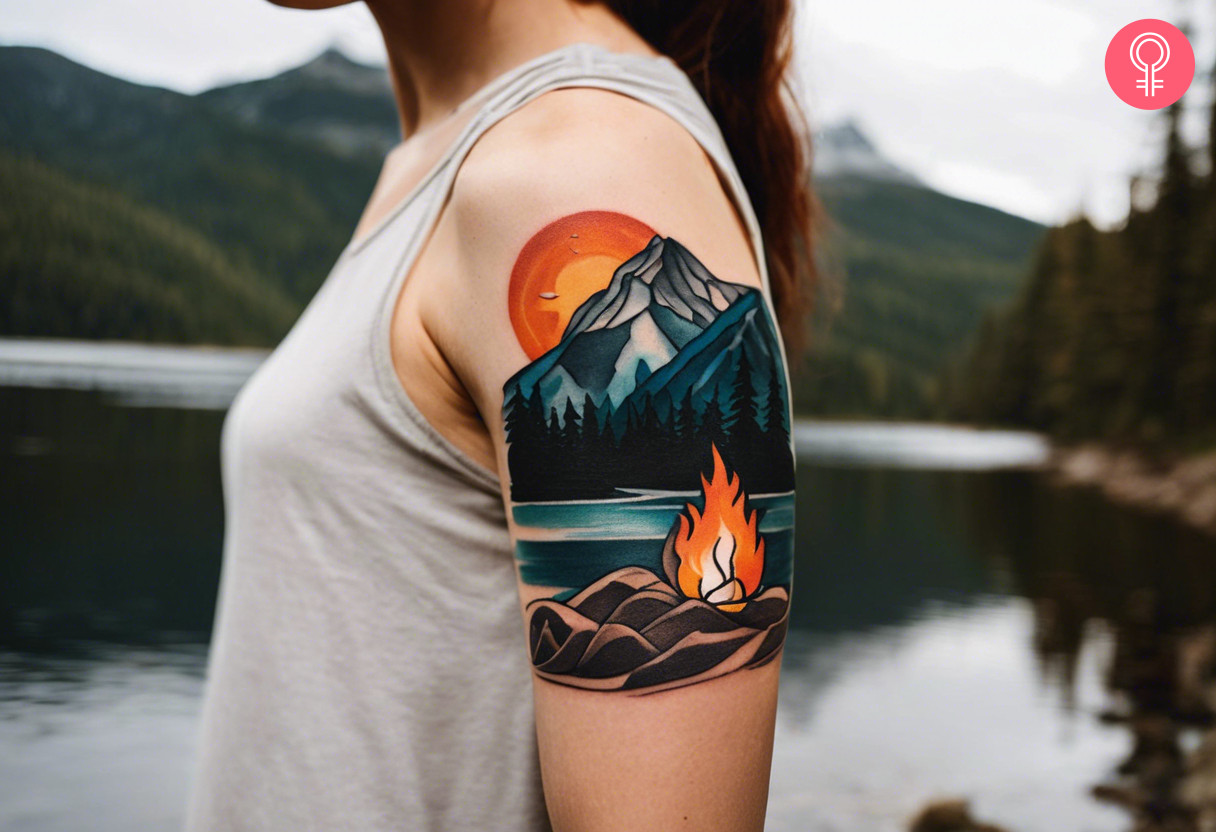 Frau mit Wildnis-Lagerfeuer-Tattoo auf ihrem Oberarm