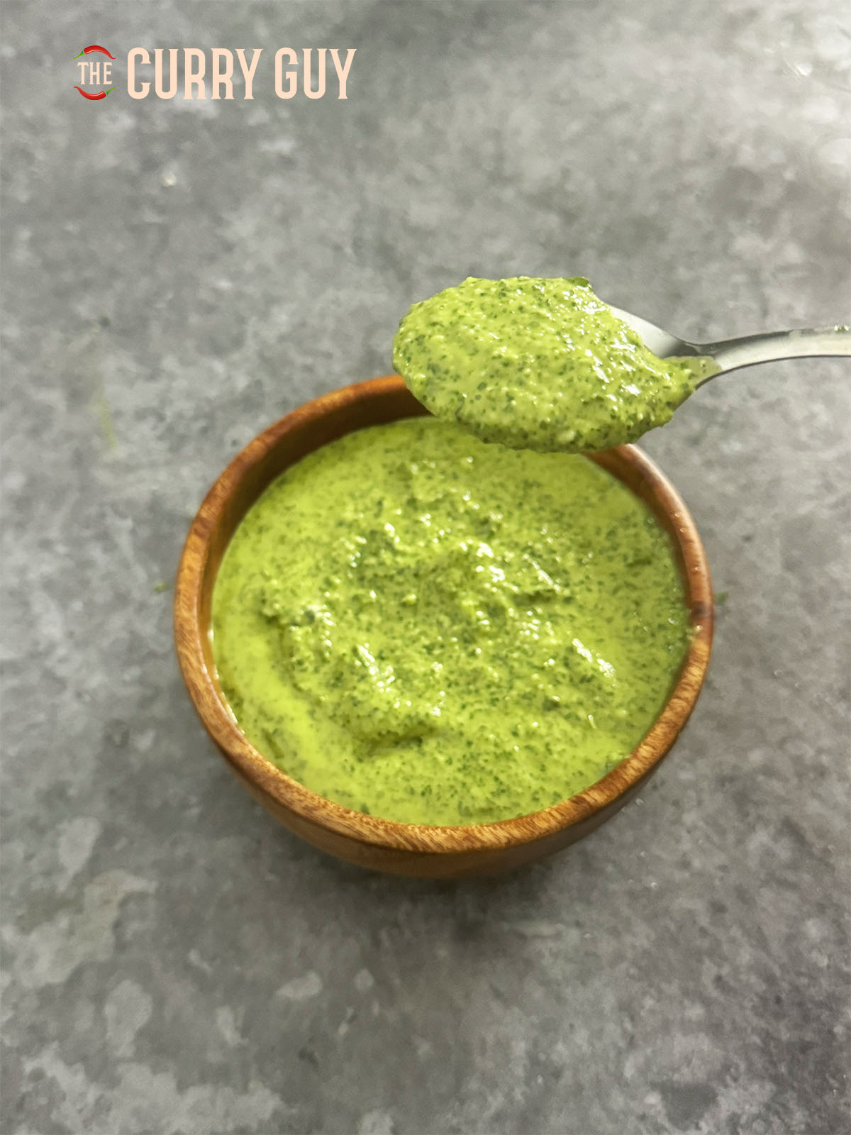 Aji Verde-Sauce in einer Schüssel. Ein Löffel zeigt die Dicke der Sauce.