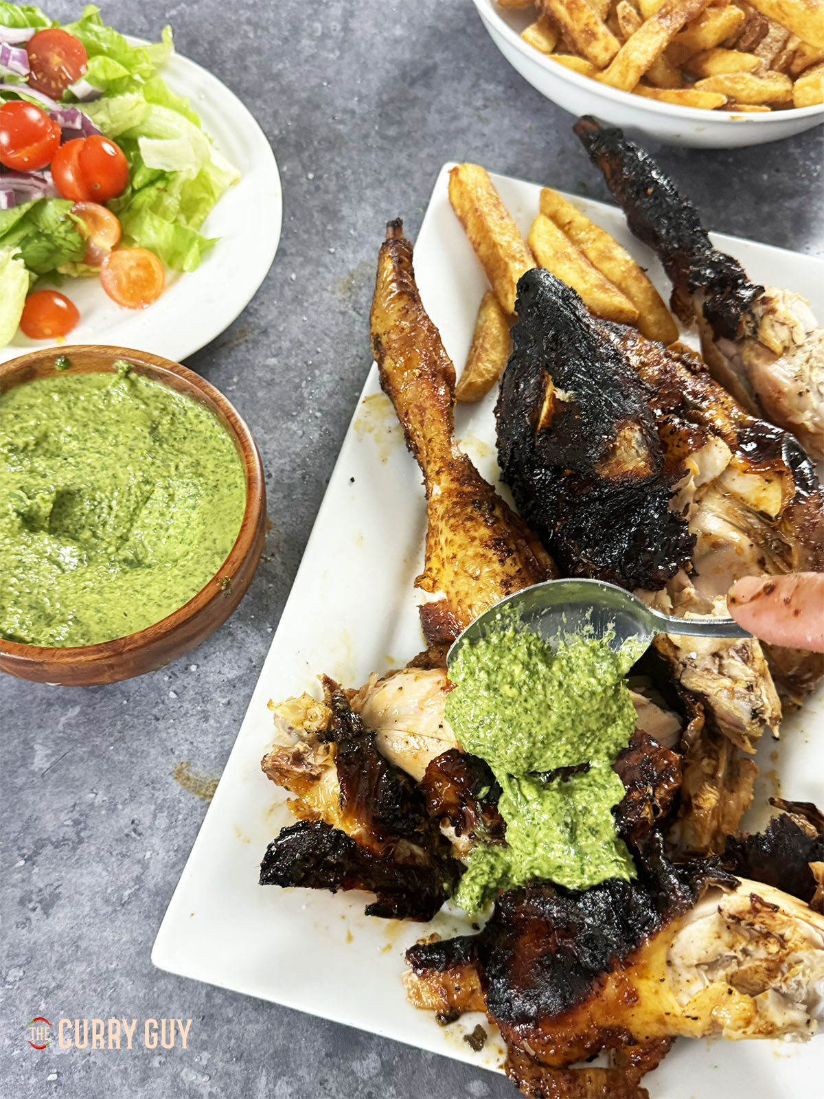 Servieren Sie das Hühnchen in Scheiben mit Pommes Frites, Aji-Verde-Sauce und Salat.