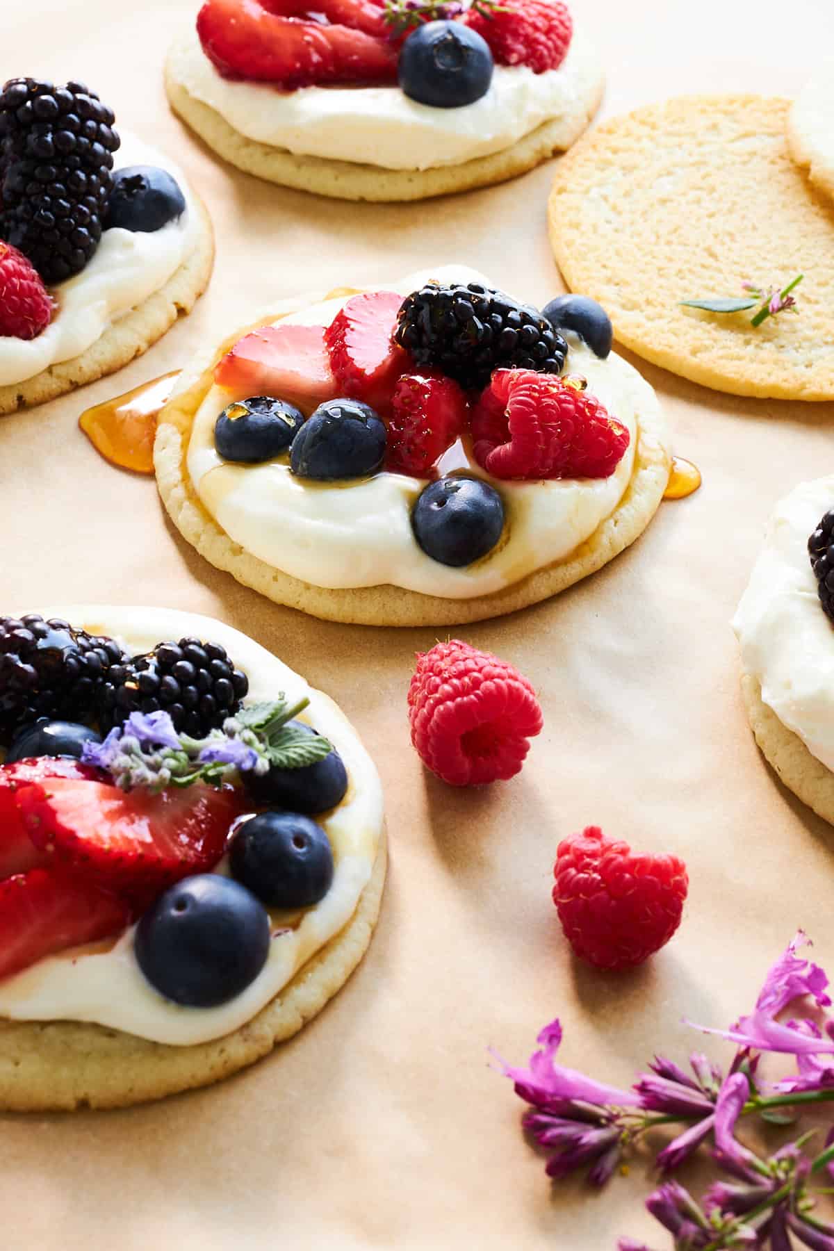 Fruchtpizzakekse mit Käsekuchenglasur, frischen Beeren und Honig. 