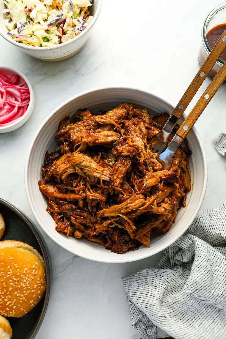 Pulled Pork mit Brötchen, Krautsalat, eingelegten Zwiebeln und BBQ-Sauce