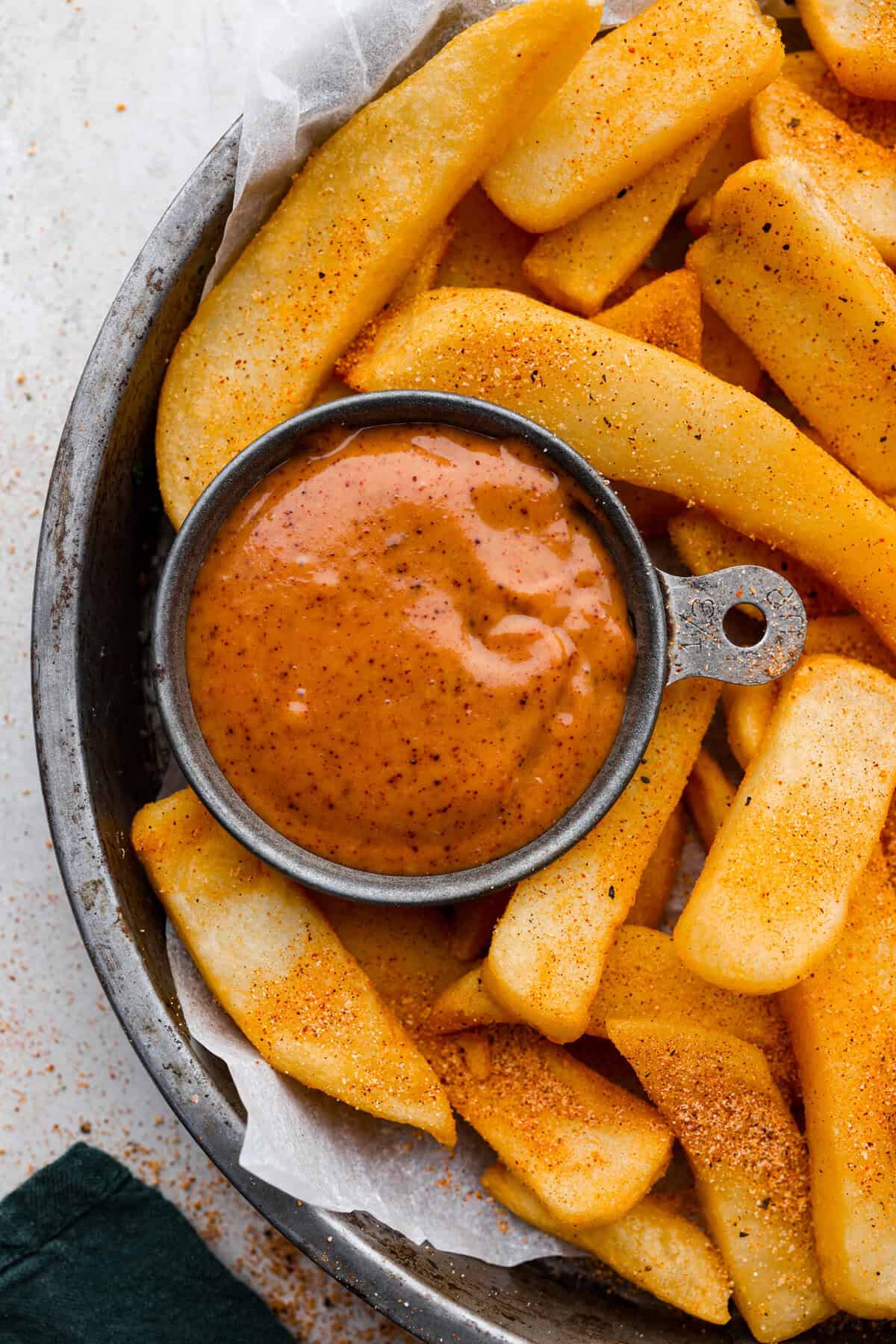 Overhead shot of seasoned french fries with a small bowl of red robin campfire sauce.